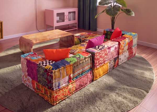Buntes Patchwork-Modulsofa, arrangiert um einen Couchtisch aus Holz auf einem runden Teppich in einem modernen Wohnzimmer.
