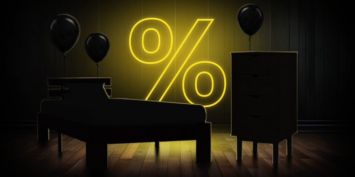  Schwarzes Bett und Kommode mit schwarzen Ballons vor einem leuchtend gelben Prozentzeichen auf dunklem Holzboden.